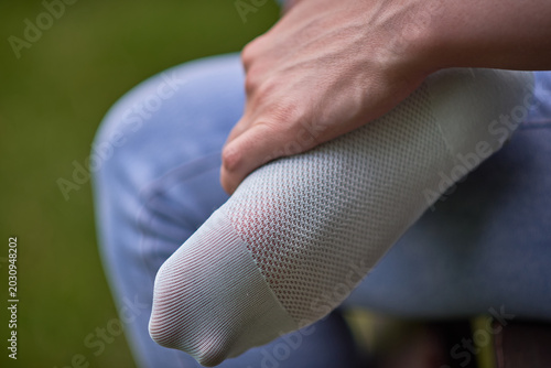 Canvas Print Close-up of torn sock on foot held by hand outdoors