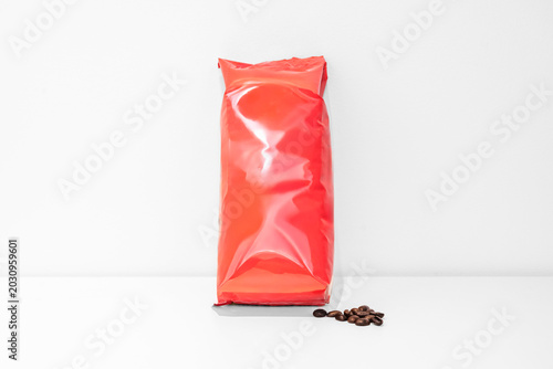 Obraz na płótnie A bright red airtight bag with coffee beans on a white surface.