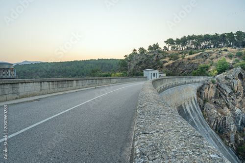 Photos A winding road of dark asphalt cuts its way between two enormous turquoise bodies of water, surrounded by hills covered in holm oaks and dry scrubland that reflect the light of the setting sun