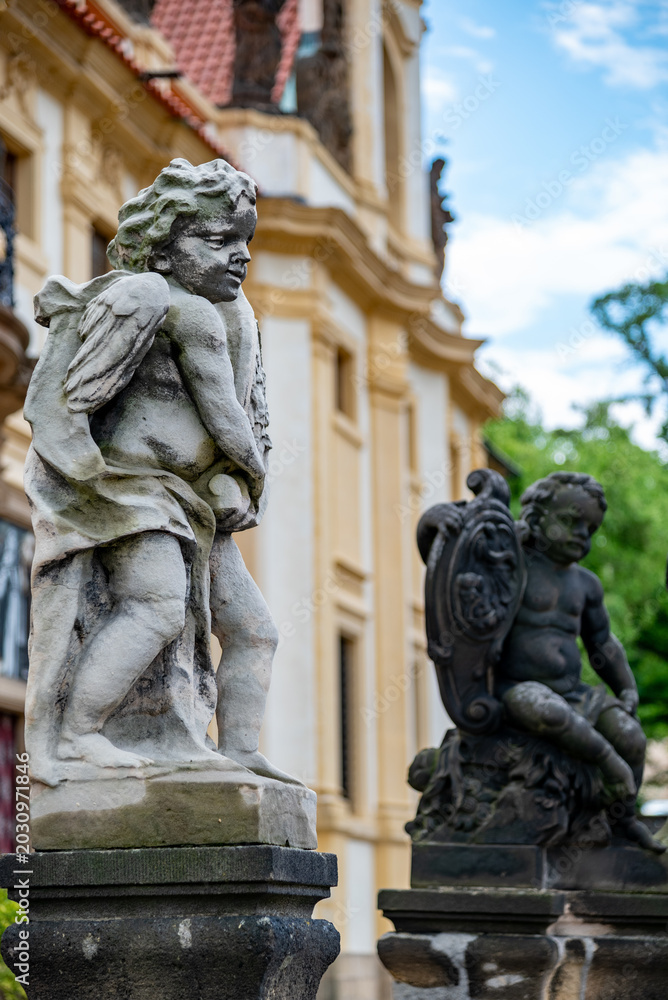 Fototapeta premium Stone cherub statues by historic palace in garden