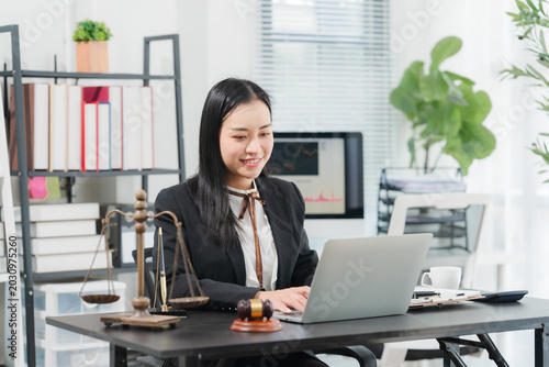 Lawyer Working at Desk: A professional female lawyer diligently works on her laptop at a well-organized desk, surrounded by legal books, a scale of justice, and a gavel.