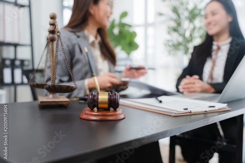 Legal Consultation in Office: A lawyer and client engage in a serious discussion in a modern office, with a gavel and scales of justice prominently displayed on the desk.