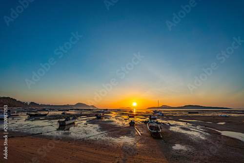 Foto A peaceful ocean panorama showcasing traditional boats under a glowing sunset horizon