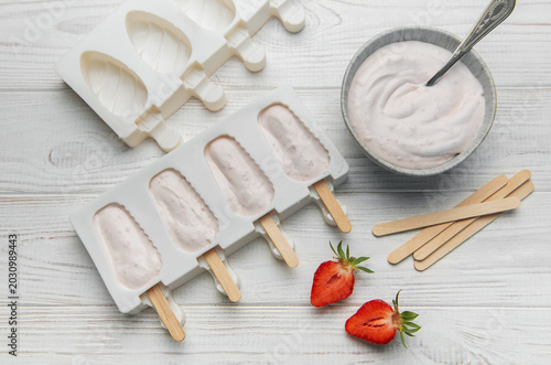 Preparing homemade strawberry popsicles in silicone molds