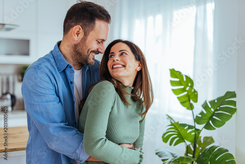 Happy Young Couple Hugging in Bright Modern Kitchen, Smiling and Sharing a Romantic Moment at Home