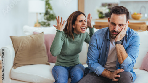 Upset Couple Arguing on Sofa in Living Room — Woman Yelling While Man Looks Frustrated
