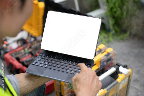 A technician in a safety vest holds a tablet with blank white screen mockup outdoors, ideal for field service, maintenance, and technology app concepts.