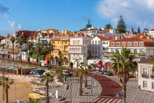 Colorful residential buildings and palm lined waterfront promenade in Cascais, Portugal.