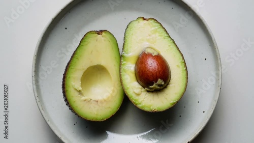 Ripe avocado halves on a minimalist ceramic plate overhead
