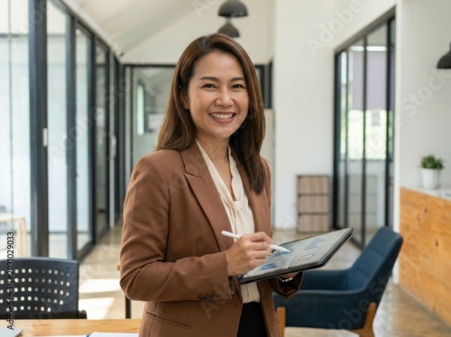 Smiling young businesswoman holding tablet in modern office