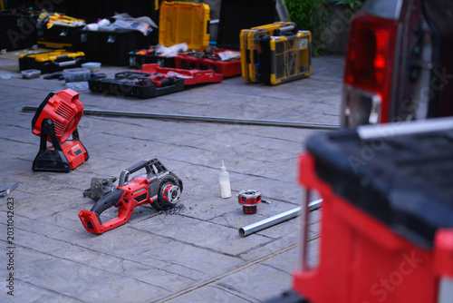 Professional Power Tools and Toolboxes Spread on Outdoor Pavement During Construction Work