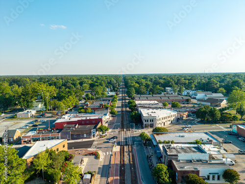 Foto Ashland, Virginia, aerial view looking straight down the historic train tracks running through the center of the downtown district lined with small businesses, trees, and roads