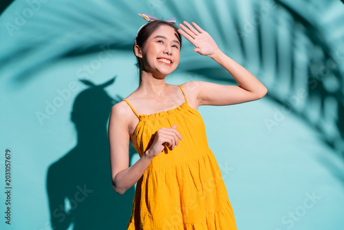 Schilderij op canvas beautiful cheerful young Asian woman in a vibrant yellow swimsuit and sunglasses