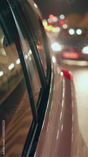 Young woman looks out of taxi window while traveling in the evening city lights