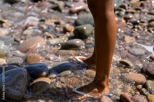 Tableau sur toile Young person wading in clear river water