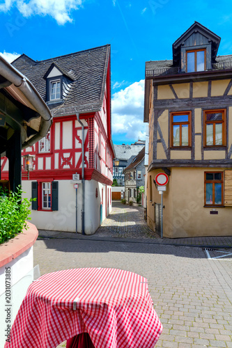 Historic half timbered houses and narrow old town alley beneath blue sky in Eltville am Rhein