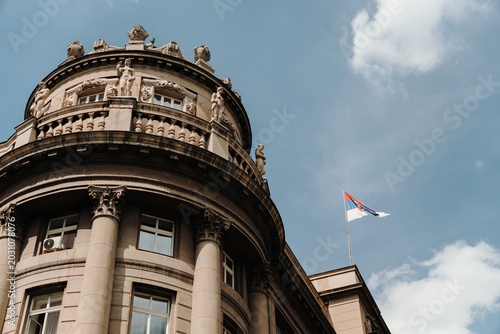 Historic government building with Serbian flag under blue sky in Belgrade Serbia. Concept of national identity, politics and state architecture