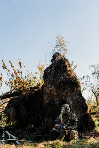 Photos Post-apocalyptic survivor or stalker in a gas mask and military camouflage holdi