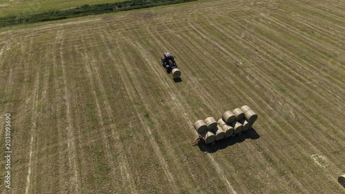 Foto Tractor Collecting Hay Bales in Field