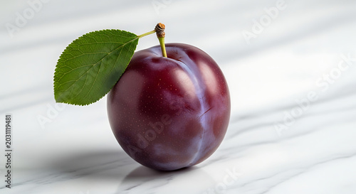Fresh ripe purple plum with green leaf on white marble background