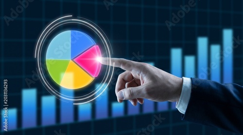 Businessman interacts with colorful pie chart on digital screen with graphs in background