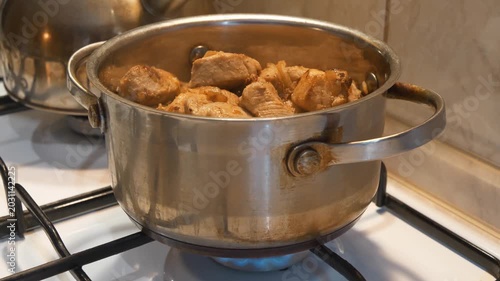Meat is stewing. There is pot of meat on gas stove. Cooking
