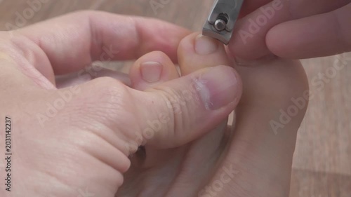 Adult man cuts his toenails using nail clipper. Foot and toes of an adult man, close-up shot video in natural light