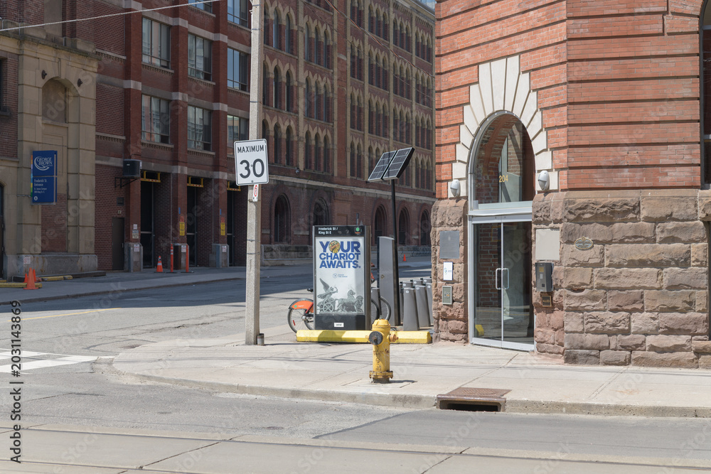 Naklejka premium looking north at crossing of Frederick St and King St E to Bike Share Toronto rental bike docking station and wayfinder at George Brown College, Toronto