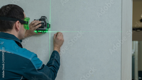Quadro em tela A man measures distance with a laser level.