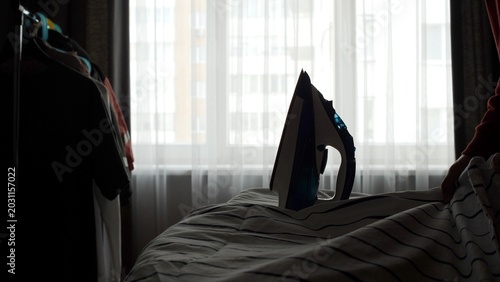 Photography Electric steam iron poised on an ironing board in a sunlit room, ready to smooth