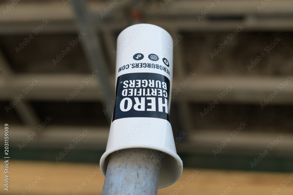 Naklejka premium discarded Hero Certified Burgers restaurant chain beverage cup on a defocused industry background, Toronto