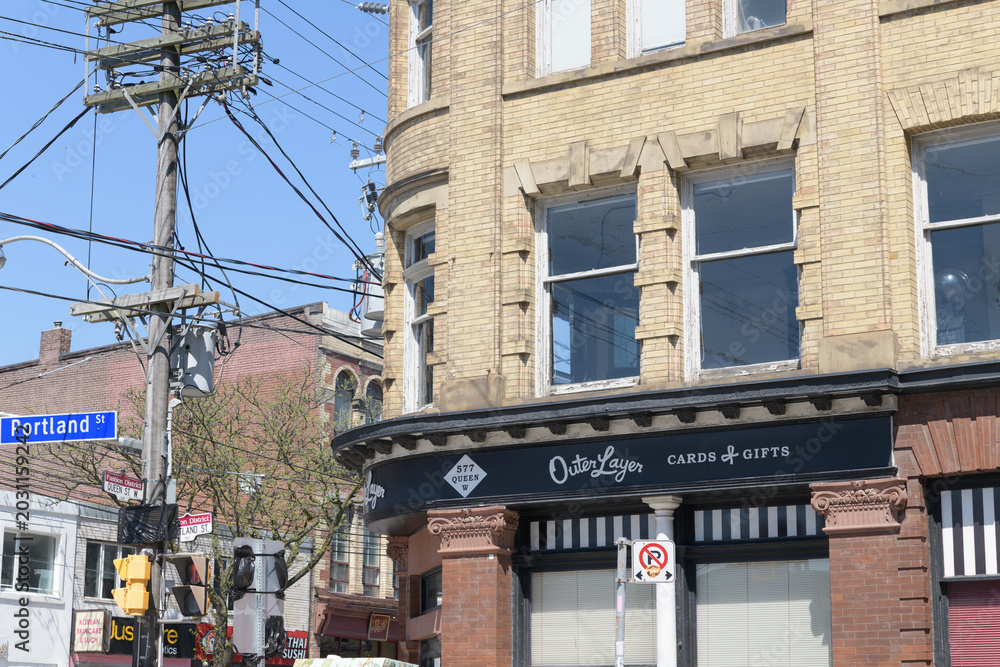 Naklejka premium exterior building facade and sign of Outer Layer, a gift shop, located at southeast corner of 577 Queen St W and Portland St, Toronto