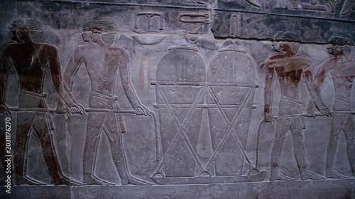 Close-up of detailed limestone relief carving inside tomb of Kagemni at Saqqara, Egypt, depicting ancient Egyptian male figures with tools, faint traces of original red pigment.