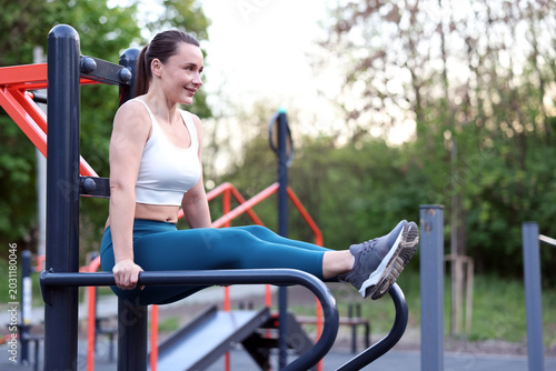 Obraz na płótnie Athletic woman exercising on parallel bars at outdoor gym