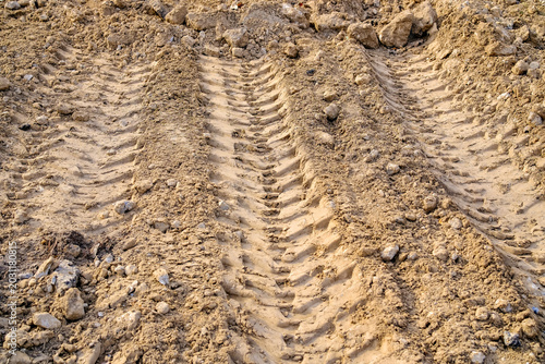 Fotografie Heavy machinery tire tracks on dry clay soil at construction site with rough tex