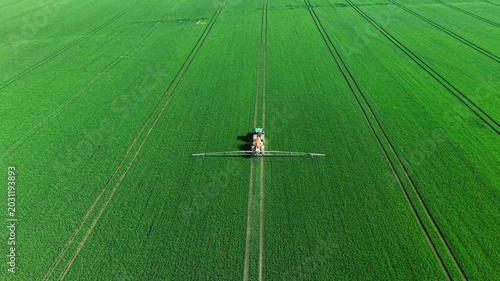 Aerial View of Tractor Spraying Vast Green Field with Converging Tramlines