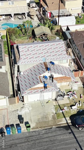 Aerial drone view of construction workers installing underlayment on a residential house roof 4k