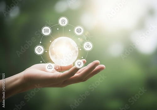 Human hand holding a luminous orb with a digital interface.