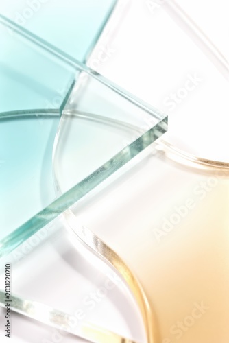 Glass panels overlapping in soft teal and amber tones on white background
