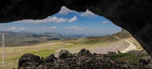 Konstfotografi View from inside Horadada Cave (Loja, Spain) looking out at a green valley and m
