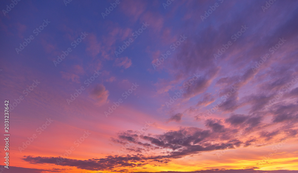 Fototapeta premium Stunning Vibrant Sunset Sky with Colorful Clouds,A breathtaking view of a dramatic sunset sky filled with vibrant shades of orange, pink, purple, and blue. Soft, scattered clouds are illuminated.