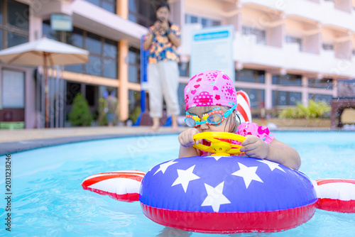 Fotografía Adorable little girl wearing a swimming cap and goggles, happily playing with a