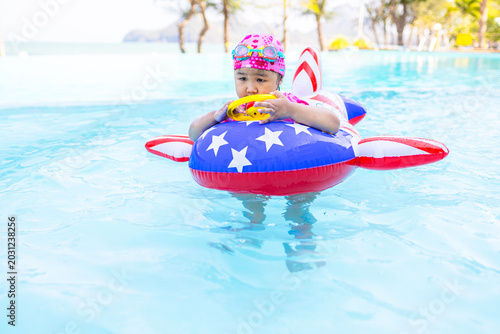 Cuadro en lienzo Adorable little girl wearing a swimming cap and goggles, happily playing with a