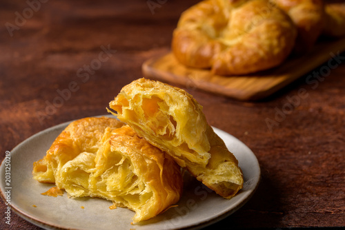 Fotografie Broken flaky croissant on white plate and dark background