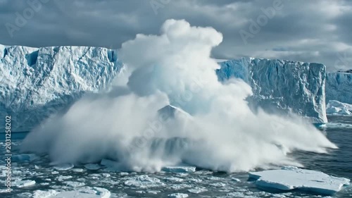 Massive iceberg calving event in the Arctic ocean with dramatic ice splash.