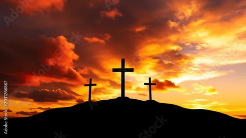Three silhouette crosses on hilltop against dramatic sunset sky