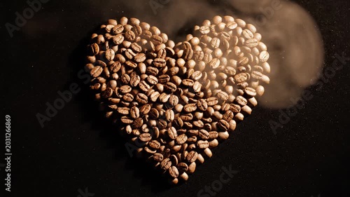 Heart shape formed by roasted coffee beans on dark background