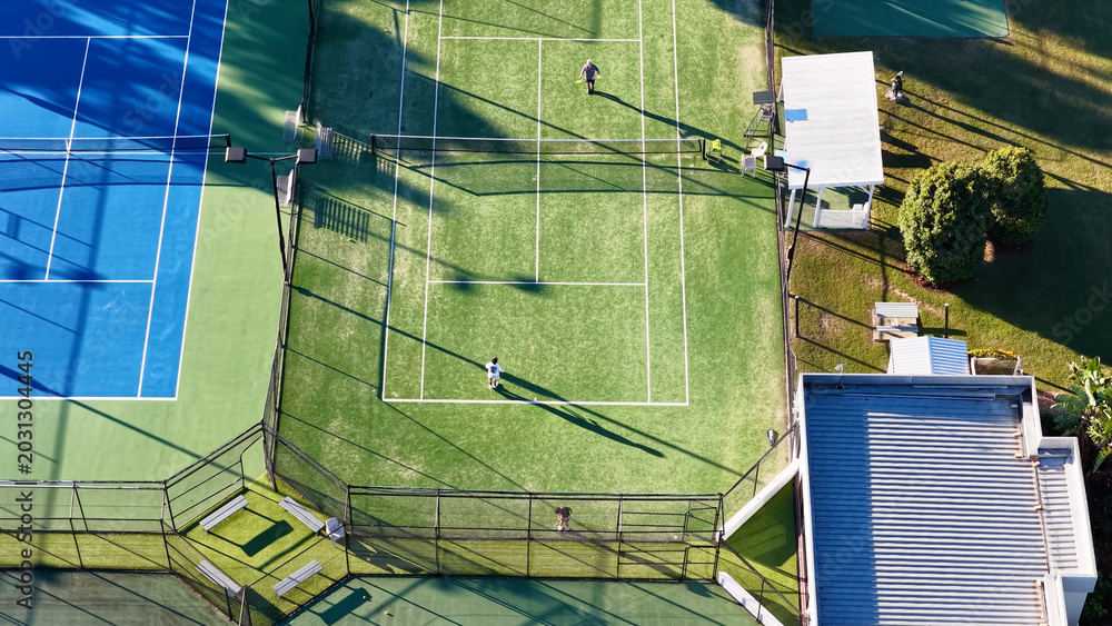 Naklejka premium Aerial View of Tennis Players on a Green Court With Long Shadows