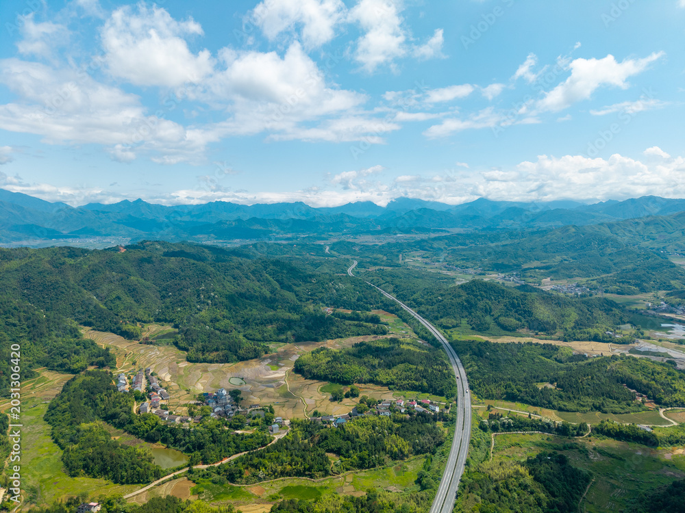 Fototapeta premium A high angle aerial view of the lush green mountains and winding roads in Wuyi Mountain in Fujian China