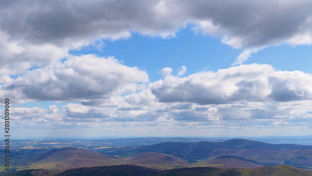 Fototapeta premium Aerial View of Rolling Scottish Highland Hills Under Dramatic Cloudscape